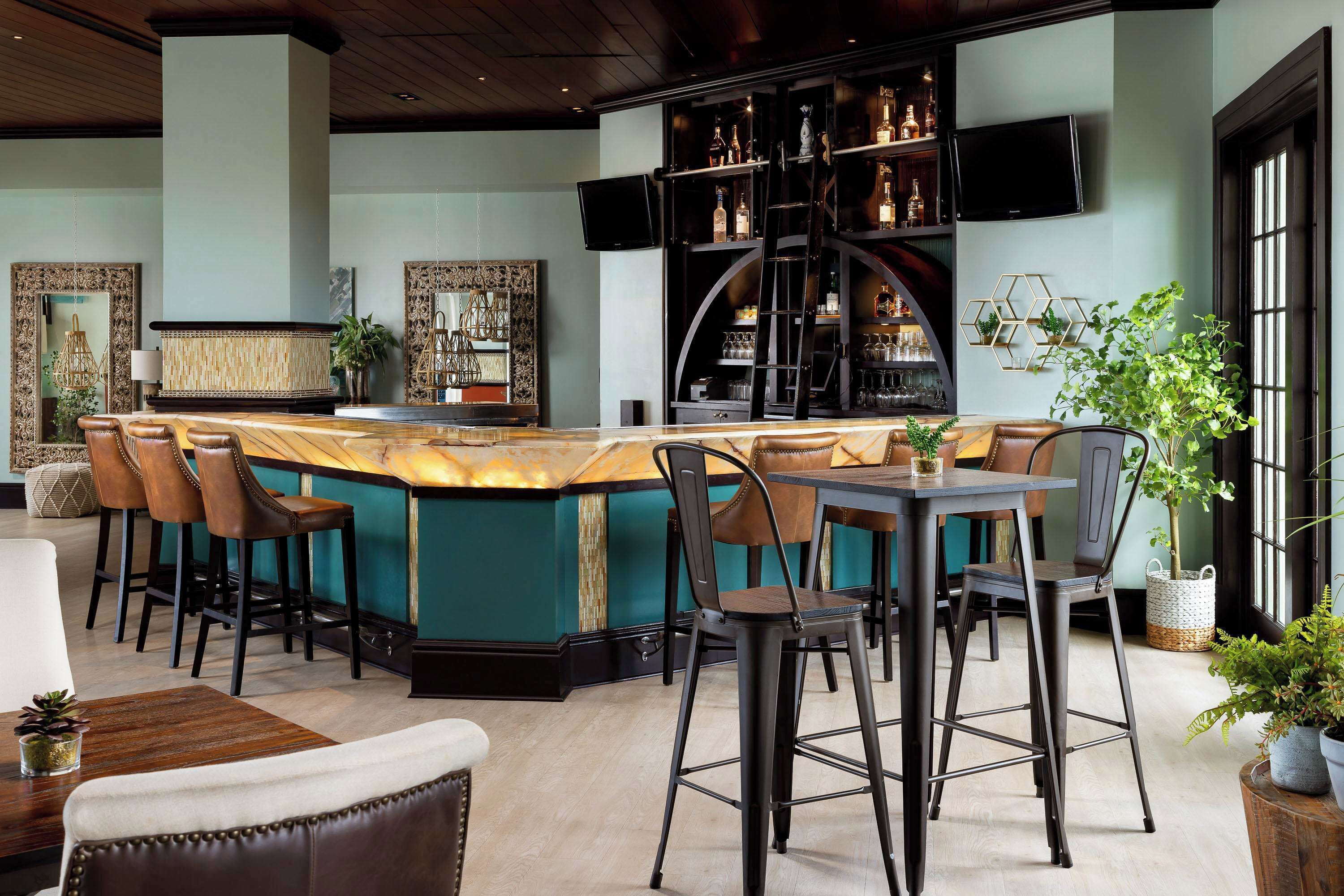 Een bar met barkrukken, een toonbank en een aan de muur bevestigde televisie.