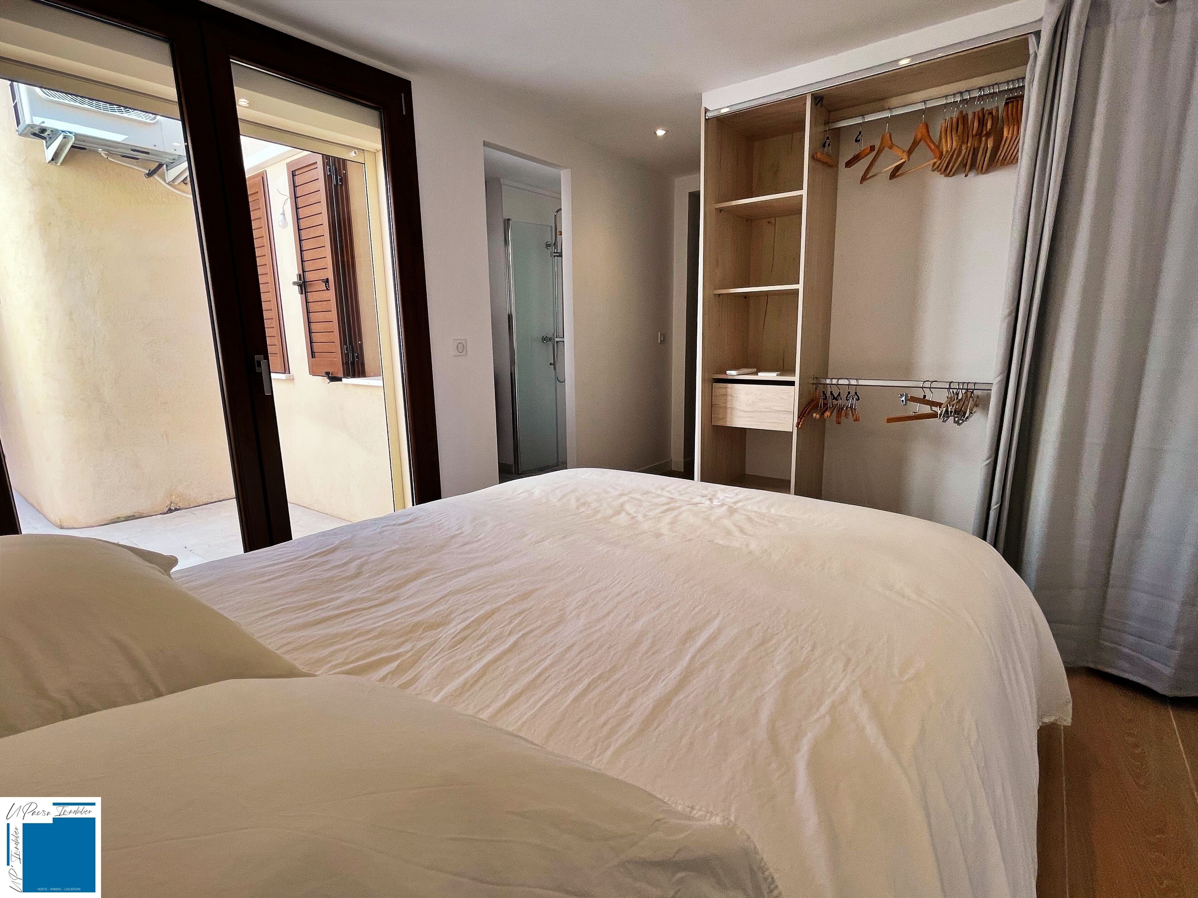 A bedroom with a large bed, a walk-in closet, and a bathroom with a glass door.