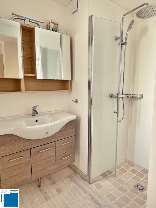 A modern bathroom with a glass-enclosed shower, a white sink, and a wooden vanity. - AIR-CONDITIONED VILLA IN SOUTHERN CORSICA: Sleeps 8, 4 Bedrooms, 150 meters from the beach (LECCI)