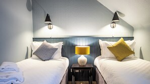 A hotel room with two beds, a nightstand with a lamp, and a patterned wall. - The Balavoulin (Aviemore)