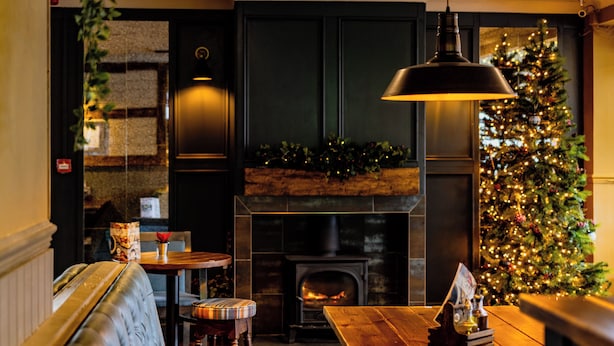 A cozy interior with a fireplace, a Christmas tree, and a bench. - The Balavoulin (Aviemore)