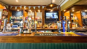 A bar with multiple taps, including brands like Heineken and Guinness, and a television screen displaying a cycling event. - The Balavoulin (Aviemore)