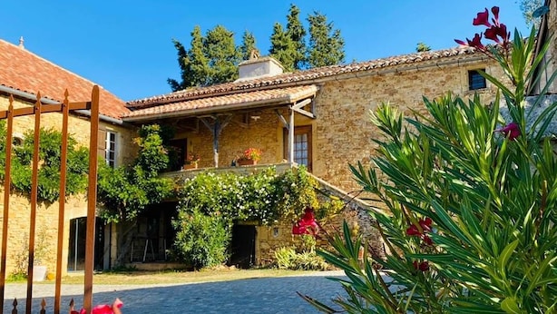 A courtyard with stone buildings, a cobblestone path, and a wooden gate. - Les Maisons du Peyrot (Loubejac)
