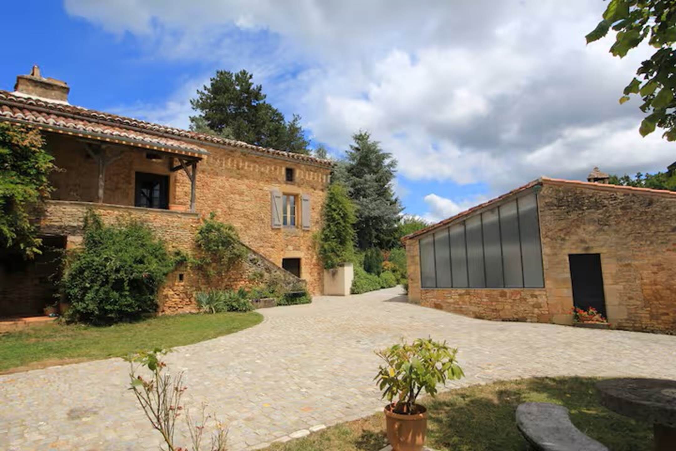 A courtyard with stone pathways, a brick building with a tiled roof, and a modern glass structure.