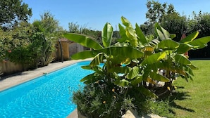 A swimming pool surrounded by lush greenery and a wooden fence. - Les Maisons du Peyrot (Loubejac)