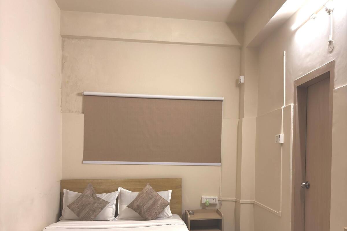 A bedroom with a bed, a ceiling fan, a bedside table, and a door.