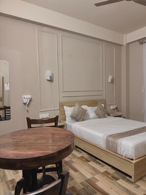 A hotel room with a wooden bed, a round dining table, and a chair. - Restel Guest House (Guwahati)