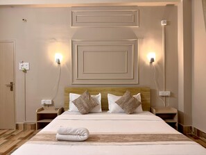 A hotel room with a neatly made bed, two bedside tables, and wall-mounted lights. - Restel Guest House (Guwahati)
