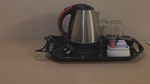 Une machine à café avec un plateau, deux verres et une dosette de café, le tout posé sur une table en bois.