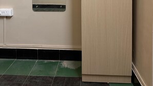 Une pièce avec une armoire de couleur claire, un petit miroir accroché au mur et une prise électrique au sol.