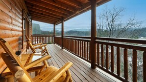 A wooden deck with a railing, wooden chairs, and a view of mountains. - Incredible Family Cabin-Gamers Lounge & Theater Rm (Sevierville)