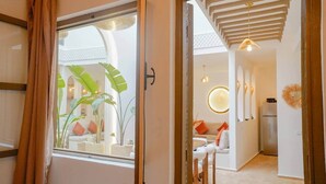 Ett modernt hotellrum med ett stort fönster, ett träpanelat tak och utsikt över innergården.
