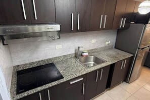 Eine moderne Küche mit dunklen Schränken, einer Granit Arbeitsplatte, einem eingebauten Herd und einer Edelstahl-Spüle.