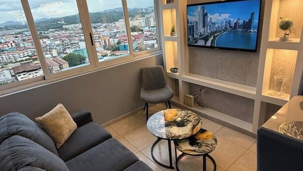 Ein modernes Wohnzimmer mit einer Couch, einem kleinen runden Tisch und einem an der Wand montierten Fernseher.