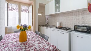A kitchen with a table set for dining, a toaster oven, and a refrigerator.