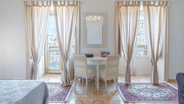 A room with a dining table, chairs, a chandelier, and a view through the window.
