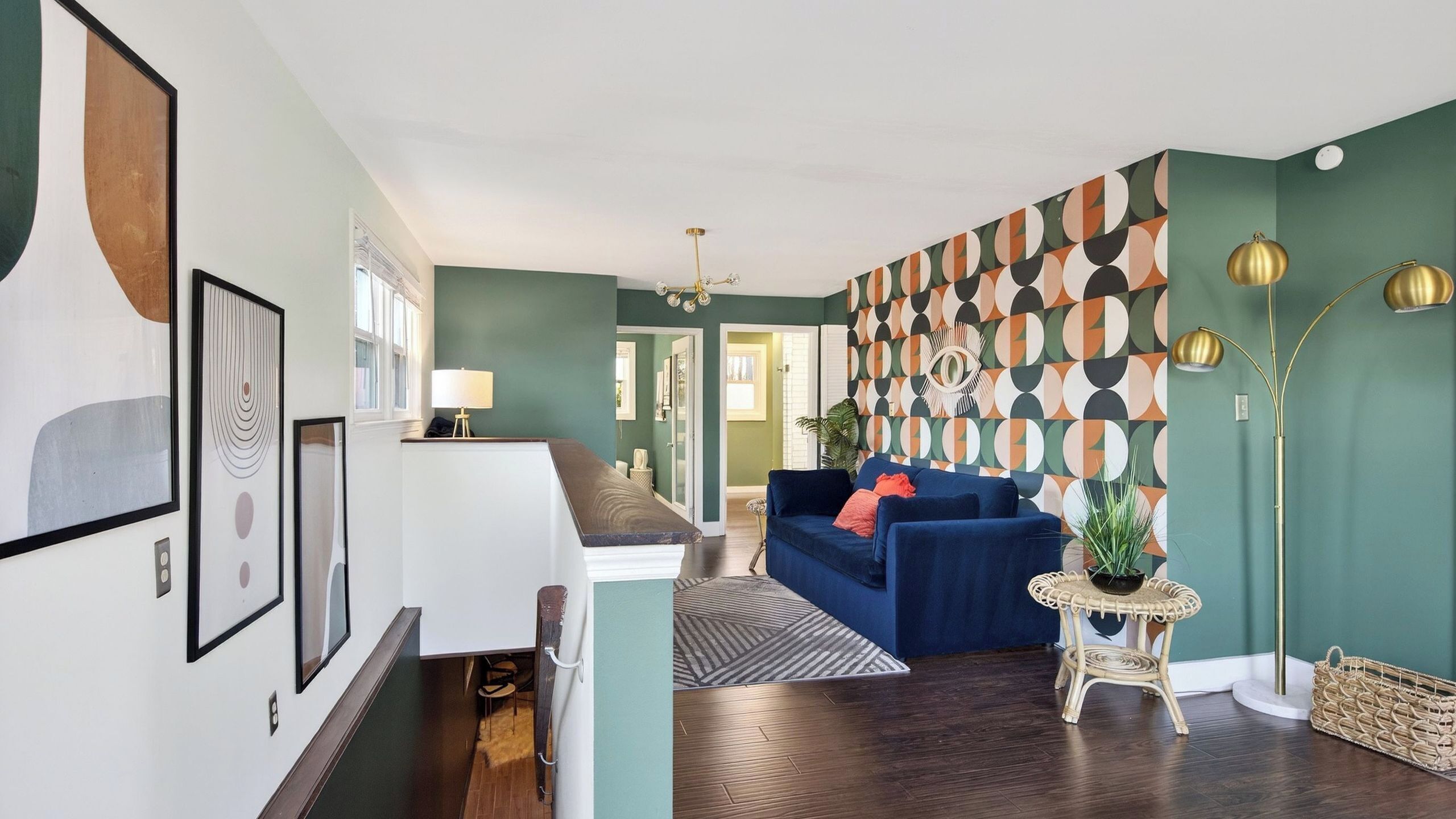 Un salon moderne avec un canapé bleu, un mur à motifs et un lampadaire.