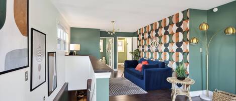 Un salon moderne avec un canapé bleu, un mur à motifs et un lampadaire.