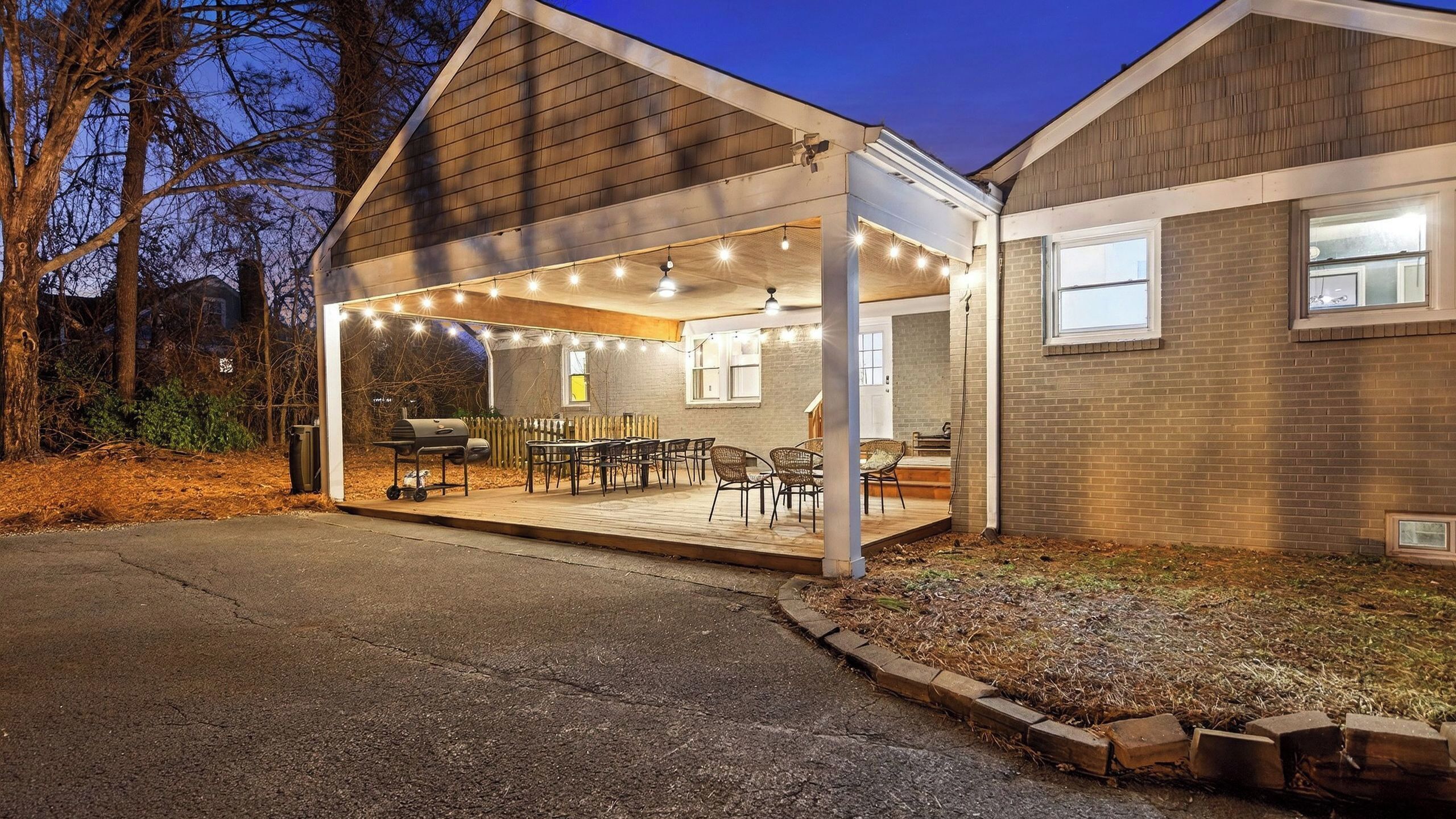 A covered patio area with string lights, a barbecue grill, and outdoor furniture.