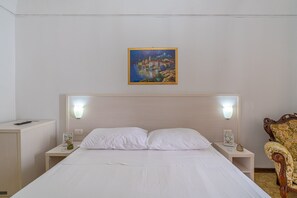 Ein Hotelzimmer mit einem Bett, zwei Nachttischen, einem Sessel und einem Bild an der Wand.