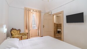 Een hotelkamer met een bed, een stoel, een televisie en een deur naar een badkamer.