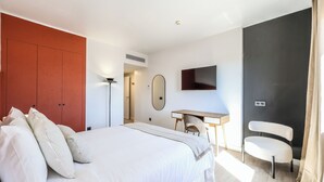 A bedroom with a bed, a desk, a chair, a TV, and a wardrobe. - Amazinn Madrid Atocha (Madrid)