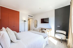 Une chambre à coucher comprenant un lit, un bureau, une chaise, une télévision et une armoire.
