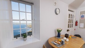 A dining area with a view of the sea, a clock on the wall, and a safety information board.