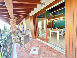 Eine überdachte Terrasse mit Essbereich, einem Steinpfeiler und Blick ins Innere.