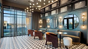 A modern interior with a checkered floor, seating areas, and a wall with vintage televisions.