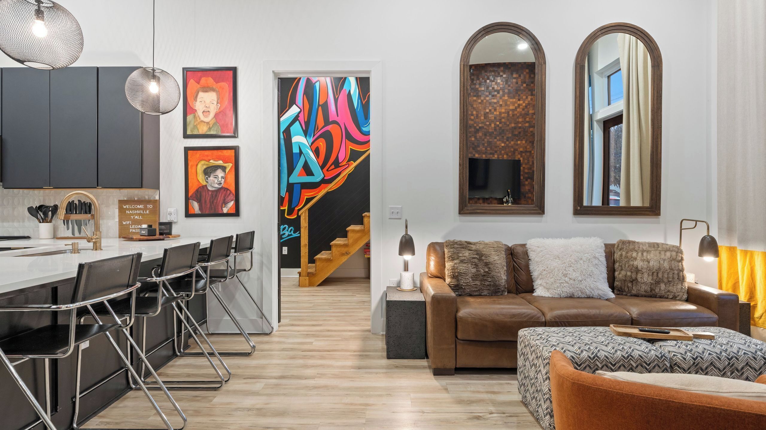 A modern living space with a kitchen, dining area, and a sofa with a TV.