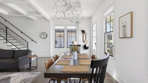Un comedor moderno con una mesa larga, sillas y una lámpara decorativa en el techo.