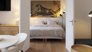 Un dormitorio con una cama, un escritorio y una silla, un cuadro de un leopardo en la pared y una lámpara.