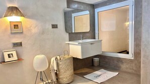 Un bagno moderno con un grande specchio, un lavandino bianco e un piccolo cestino.