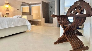 Una camera d'albergo moderna con un letto, un bagno e una sedia di legno particolare.
