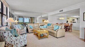 Ein geräumiges Wohnzimmer mit einer großen Couch, einem Couchtisch und einem Essbereich mit Stühlen und einem Tisch.