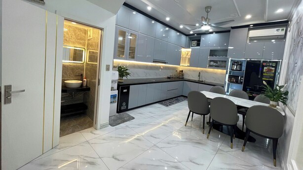 A modern kitchen with a dining area, marble flooring, and built-in appliances. - Happy House ( Villa & Apartment ) ! (Cat Ba , Cat Hai)