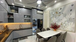 A modern kitchen with a dining area, featuring a white marble countertop, grey cabinets, and a ceiling fan. - Happy House ( Villa & Apartment ) ! (Cat Ba , Cat Hai)