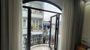 A room with a balcony, a marble floor, and a view of a building with a blue roof. - Happy House ( Villa & Apartment ) ! (Cat Ba , Cat Hai)