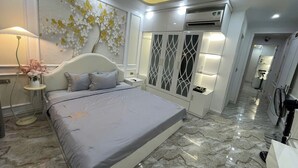 A modern bedroom with a large bed, a bedside table with a lamp, decorative wall art, and a wardrobe with built-in lighting. - Happy House ( Villa & Apartment ) ! (Cat Ba , Cat Hai)