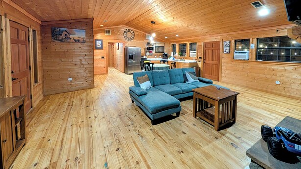 Interior de una cabaña de madera con sala de estar que incluye un sofá, una mesa de centro y una mesa de comedor.