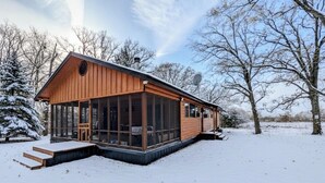 Una cabaña de madera con ventanas amplias, una chimenea y una antena parabólica.