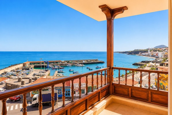 A balcony with a view of a coastal town, a harbor with boats, and a clear blue sky. - Neptuno Apartment in the Center of Candelaria (Candelaria)