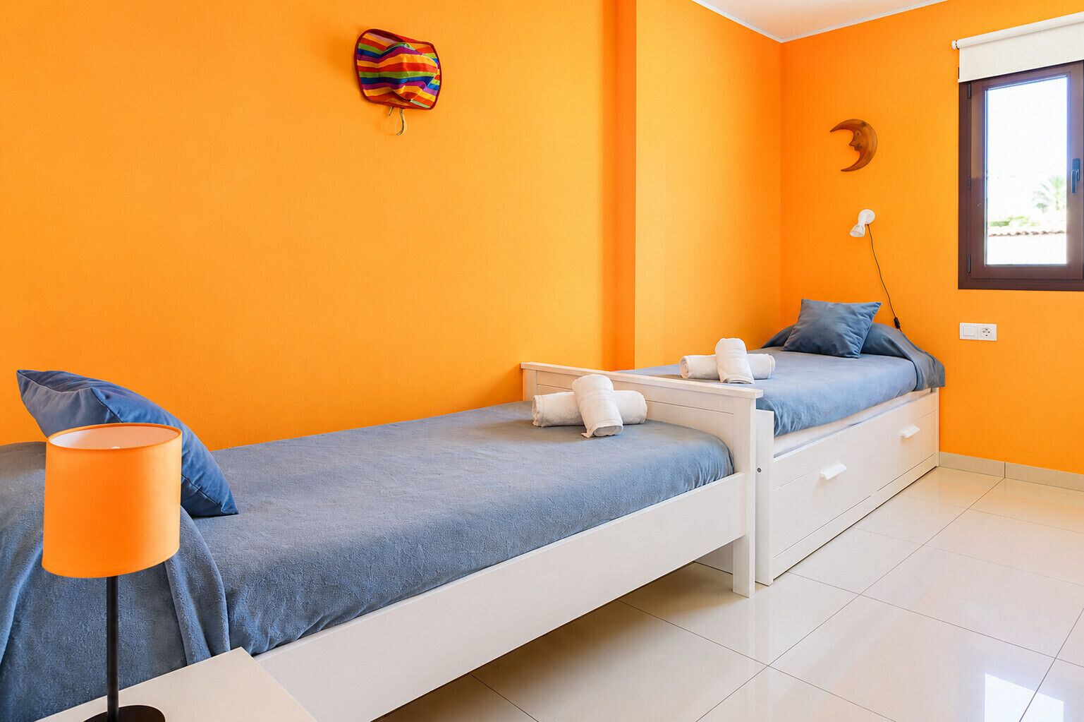 Habitación con cama individual, una mesita de noche, una lámpara y ventana con vistas.