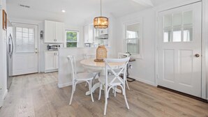 A kitchen with white cabinets, a round dining table, and white chairs. - Margate Bungalow by the Beach Entire Home (Margate City)