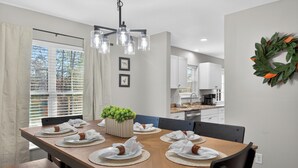 A dining area with a wooden table set for six, a potted plant, and a kitchen in the background. - Right on parkway! Playground~Hot Tub~Fire Pit (Pigeon Forge)