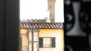 A view of a tower with a clock, a building with a balcony, and a window with shutters. - Between Duomo and Tower of Arnolfo, double view (Firenze)