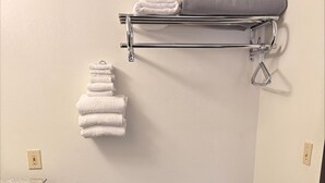 Une salle de bain avec un banc, un porte-serviettes et un plan de travail.