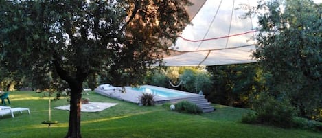 Um quintal com piscina, uma árvore e uma tenda.