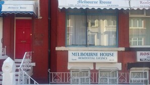 A red building with a white awning and a red door. There is a sign that reads "Melbourne House Residential Licence" and another sign that says "Roslyn". - MIdway Hotel  (Blackpool)
